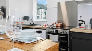 A modern kitchen with a wooden countertop, stainless steel appliances, and a view of a residential building through a window. - TYME Suites on Humber (Cleethorpes)