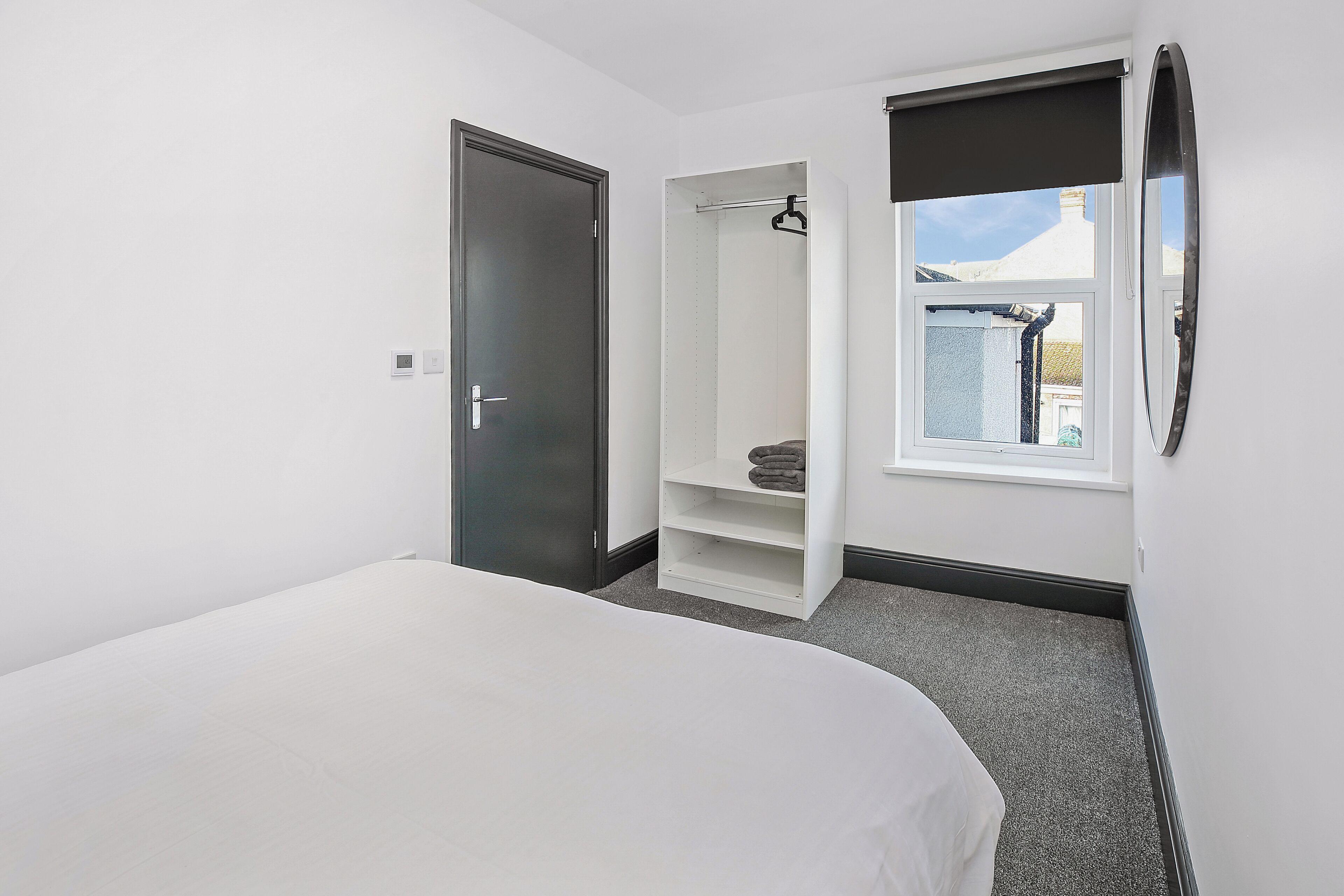 A bedroom with a bed, a wardrobe, a window, and a door.
