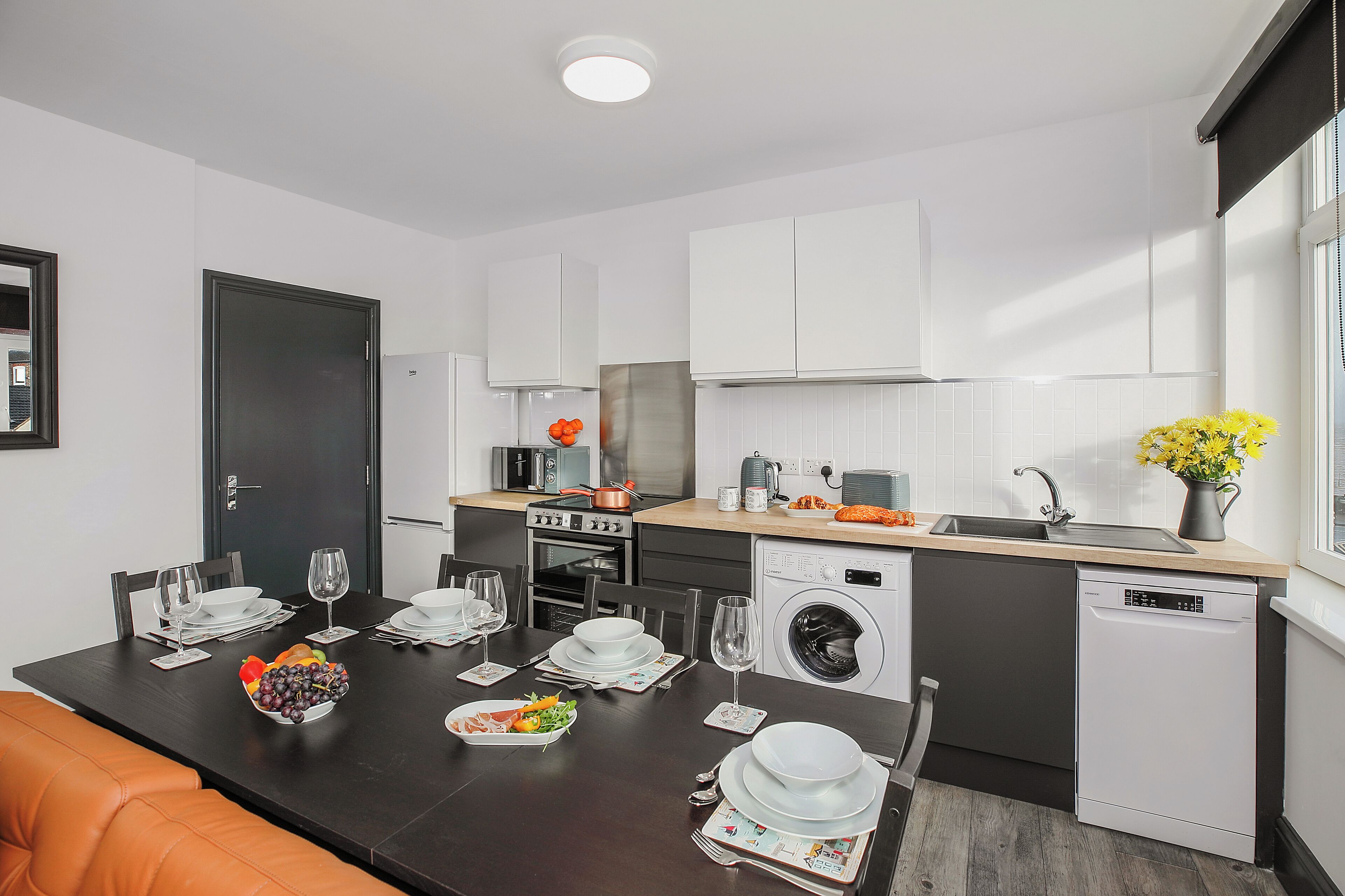A modern kitchen with white cabinets, a dishwasher, and a sink.