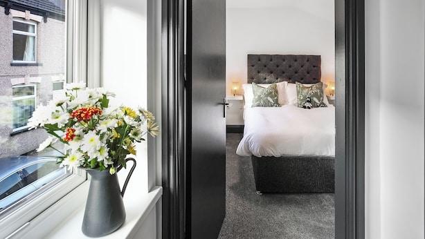 A hotel room with a bed, bedside table, and a window with a view of the outside. - TYME Suites on Humber (Cleethorpes)