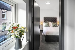 A hotel room with a bed, bedside table, and a window with a view of the outside. - TYME Suites on Humber (Cleethorpes)