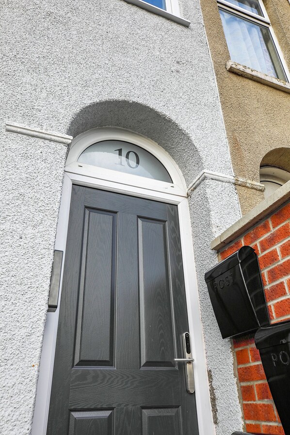 A dark wooden door with a white frame, a number '10' above it, and a small black mailbox to the right. - TYME Suites on Humber (Cleethorpes)