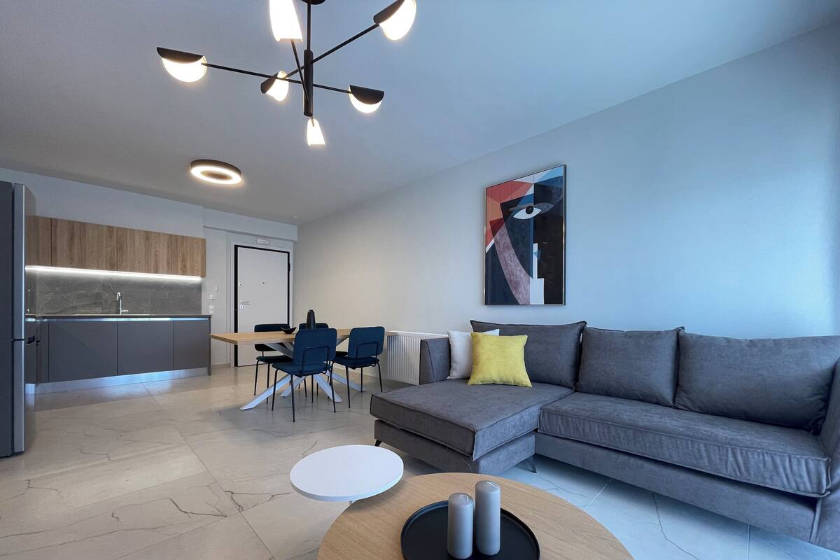 Una sala de estar moderna con un sofá gris, una mesa de centro y un comedor con sillas y una mesa.