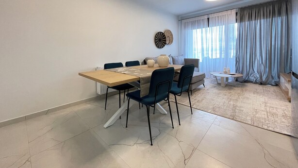 Un espace repas moderne avec une table en bois, des chaises bleues et un canapé.
