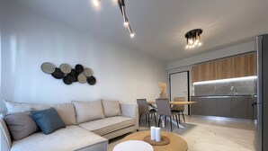 Een moderne woonkamer met een bank, een salontafel en een eethoek met stoelen en een tafel.