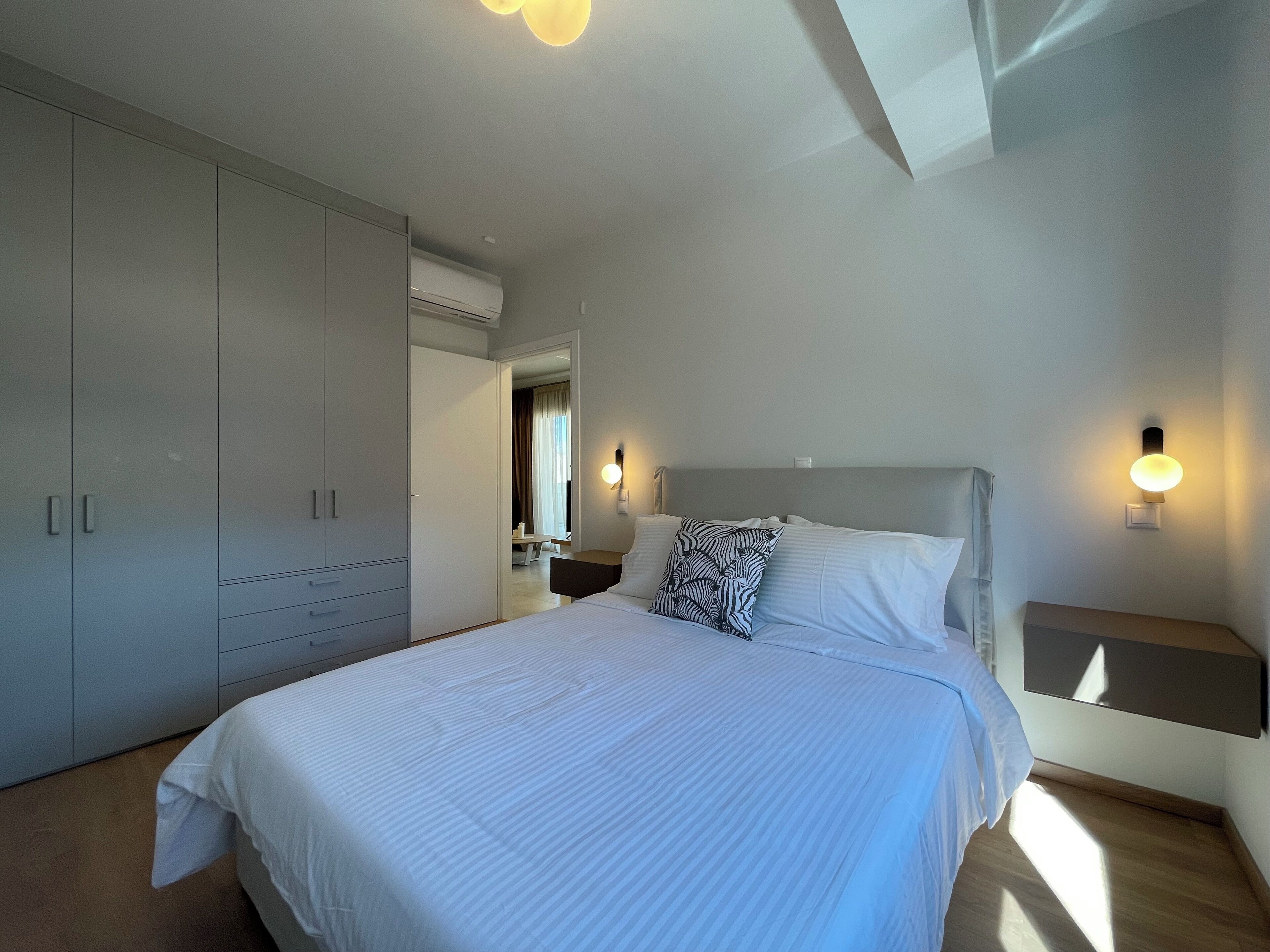 A bedroom with a large bed, a wardrobe, and a nightstand.