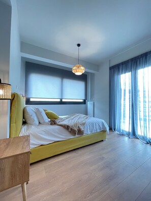 A bedroom with a bed, a window, and a hanging light fixture. - Urban Oasis in Ellinikon (Elliniko-Argyroupoli)