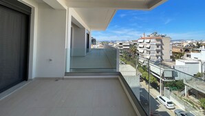 Een balkon met een helder uitzicht op de stadsgezicht, inclusief gebouwen en geparkeerde auto's.