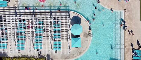 A large outdoor swimming pool with multiple lanes, surrounded by lounge chairs and umbrellas.