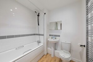 A bathroom with a white bathtub, a sink, and a toilet.