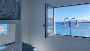 Una stanza con una grande finestra che si affaccia sul mare e sulle montagne lontane.
