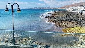 Vista della costa con acque blu cristalline, un litorale roccioso e edifici sullo sfondo.