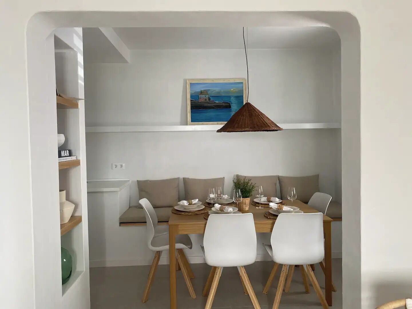 Een eetgedeelte met een houten tafel, witte stoelen en een hangende lamp.