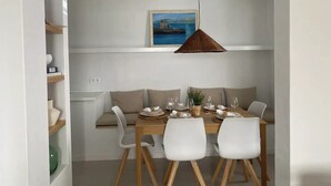 Zona pranzo con tavolo in legno, sedie bianche e lampadario.