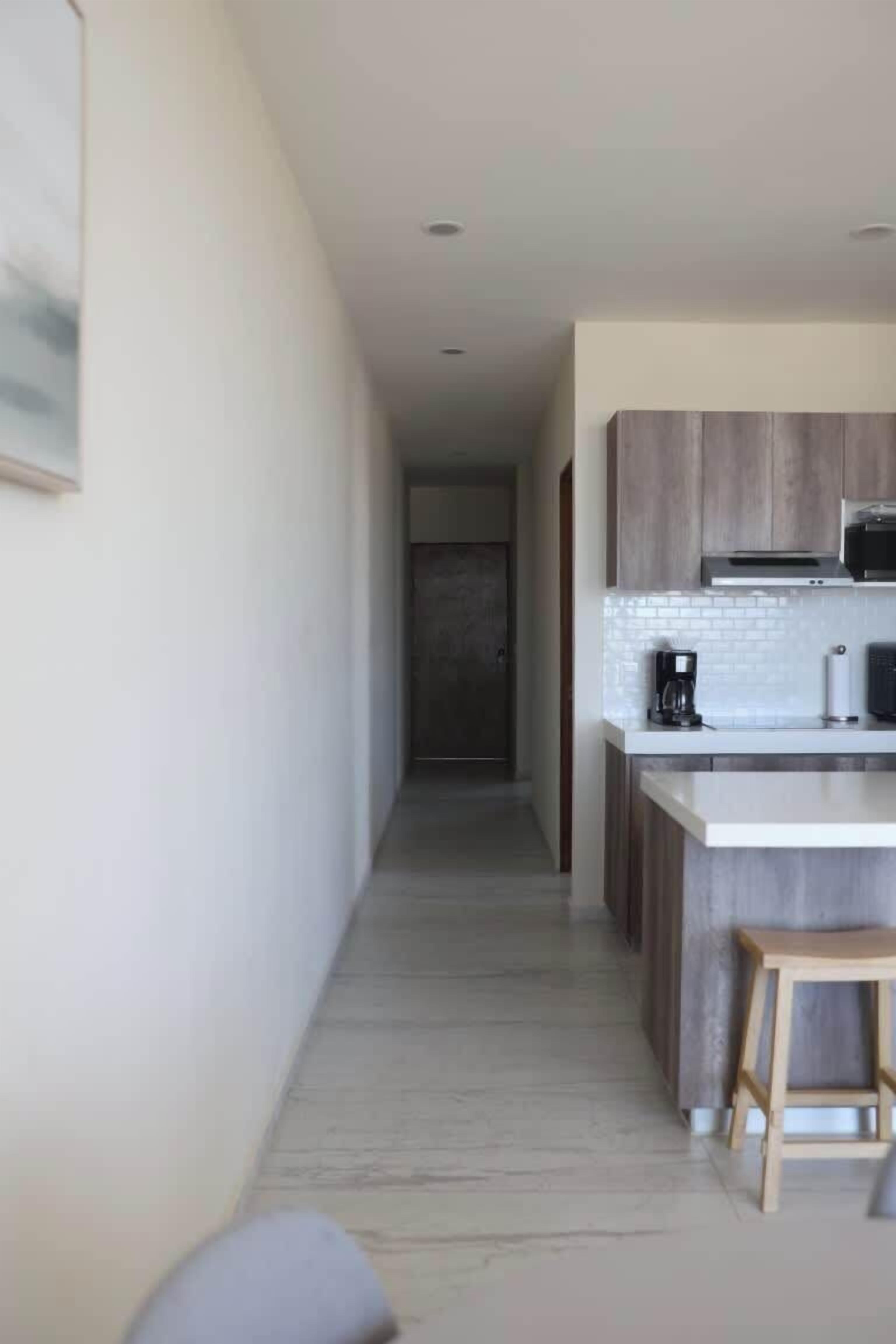 Une cuisine moderne avec un plan de travail blanc, des armoires en bois et un four à micro-ondes.