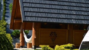 Une cabane en bois avec un toit en pente, un hamac et un motif décoratif sur le mur avant.