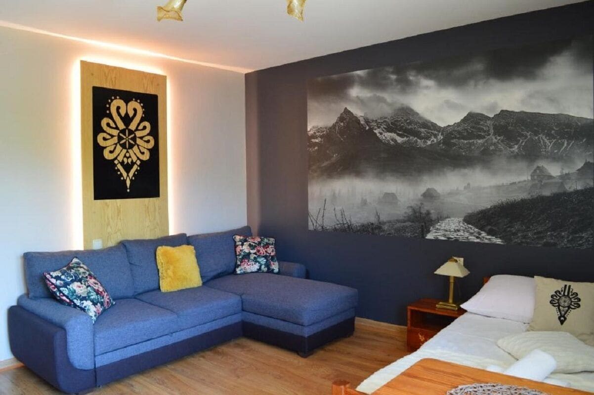 Una camera da letto moderna con un divano a divano blu, un letto grande e un murale con un paesaggio montano.