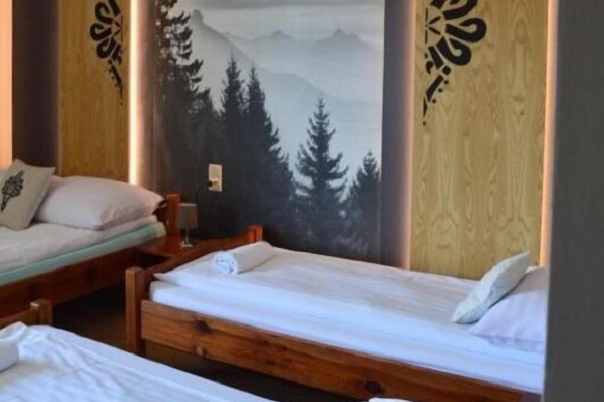 A room with two wooden beds, a large wall mural of a mountain landscape, and decorative wooden panels with script.