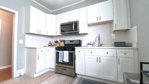 Una cocina moderna con armarios blancos, electrodomésticos de acero inoxidable y un microondas.