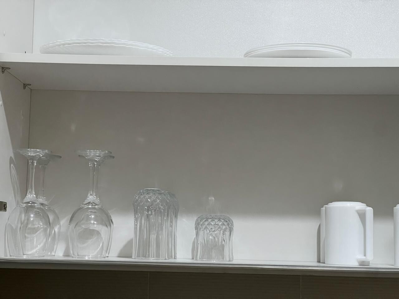 Een plank met verschillende glazen en een witte bak.