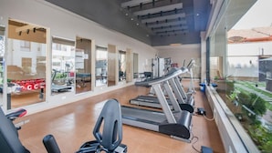 Et moderne fitnesscenter med løbebånd, træningsudstyr og store vinduer med udsigt over det udendørs område.