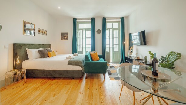 A modern bedroom with a large bed, a glass dining table, and a TV. - Downtown Suites by Vacationy (Porto)