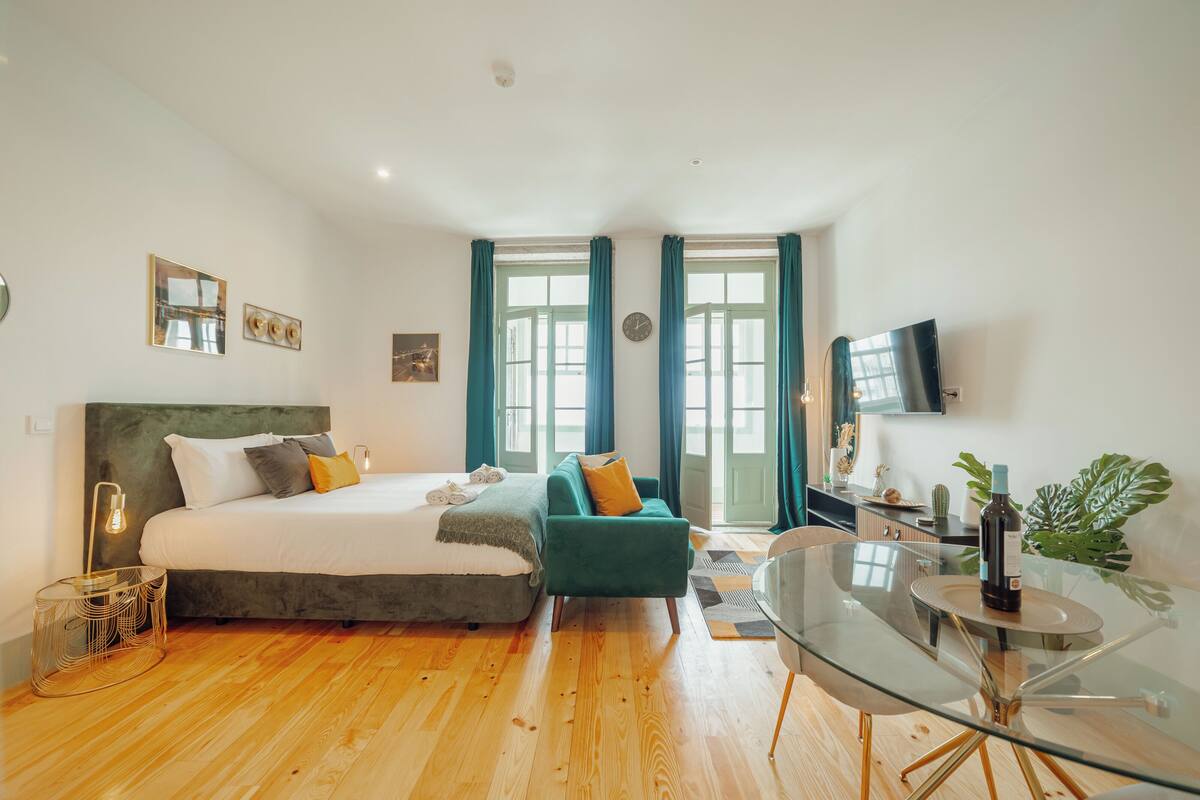 Une chambre moderne avec un grand lit, une table à manger en verre et un téléviseur.