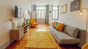 A modern living room with a sofa, a yellow rug, a TV, and a plant. - Downtown Suites by Vacationy (Porto)