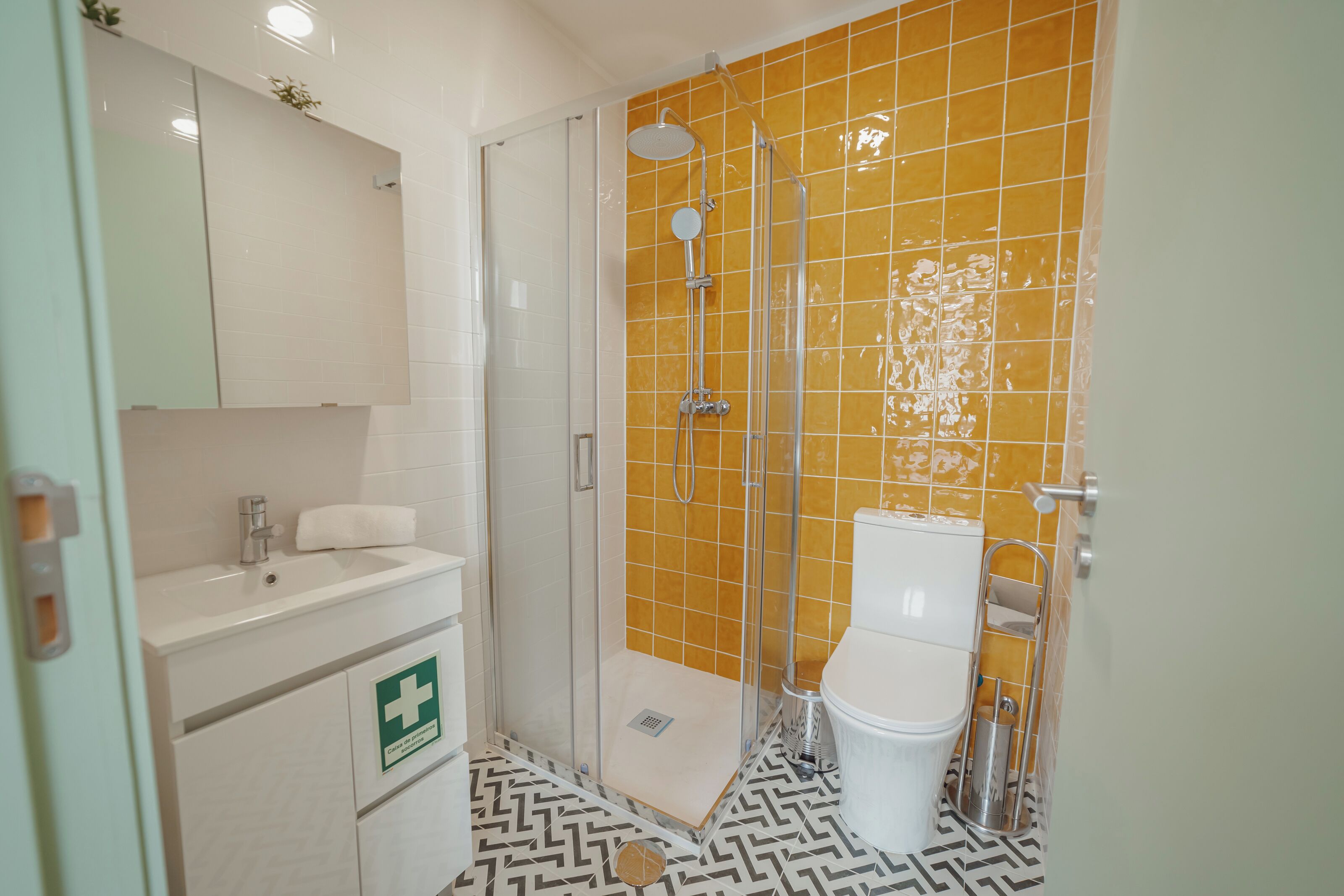 A bathroom with a shower, toilet, sink, and a first aid sign.