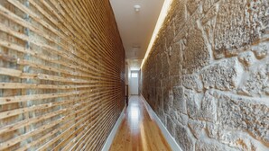 A narrow hallway with wooden flooring, a brick wall on one side, and a wooden slatted wall on the other. - Downtown Suites by Vacationy (Porto)