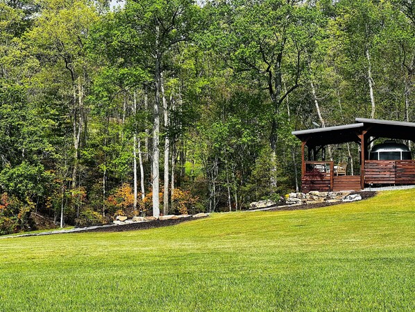 Eine Holzhütte mit überdachter Veranda, umgeben von einer Wiese und dichtem Wald.