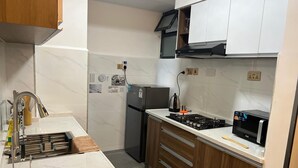 A compact kitchen with a sink, stove, microwave, and refrigerator. - Valley Heights Apartments by Bliss Haven (Nairobi)