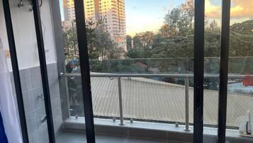 Un balcón con barandilla metálica, vista de un edificio con tejado ondulado y cielo despejado.