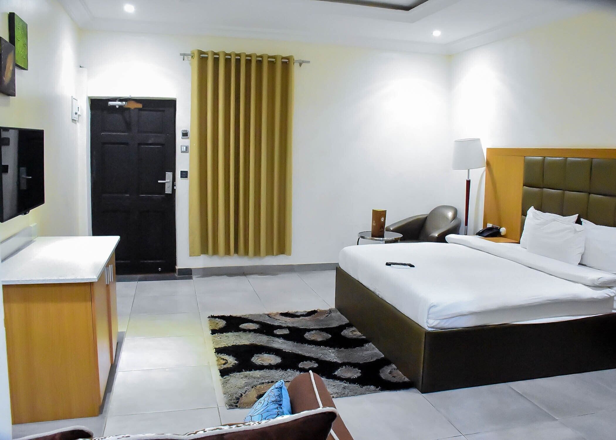 A hotel room with a bed, bedside table, lamp, and a desk with a chair.
