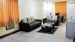 A living room with two black sofas, a coffee table, and a TV stand. - Yewa Frontier Hotel (Ibese)