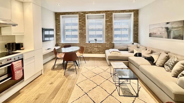 A modern kitchen with a dining area, a sofa, and a coffee table. - Bright 1Bed Flat Covent Garden (Greater London)