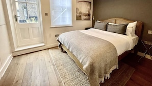 A bedroom with a bed, a window, a door, and a wall-mounted artwork. - Bright 1Bed Flat Covent Garden (Greater London)