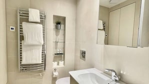 A modern bathroom with a large sink, a toilet, and a towel rack with towels. - Bright 1Bed Flat Covent Garden (Greater London)