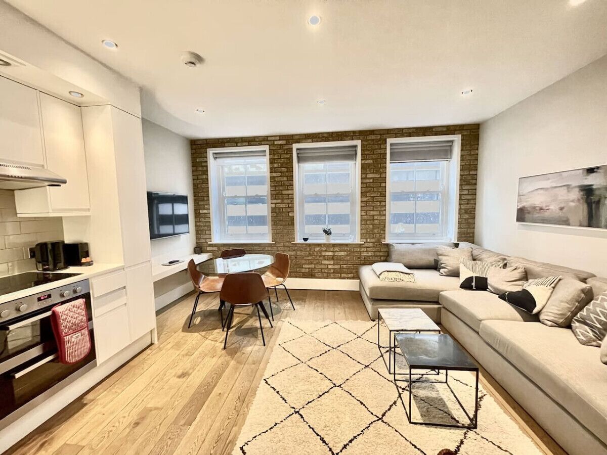 A modern kitchen with white cabinets, a dining table with chairs, and a large window with a view.
