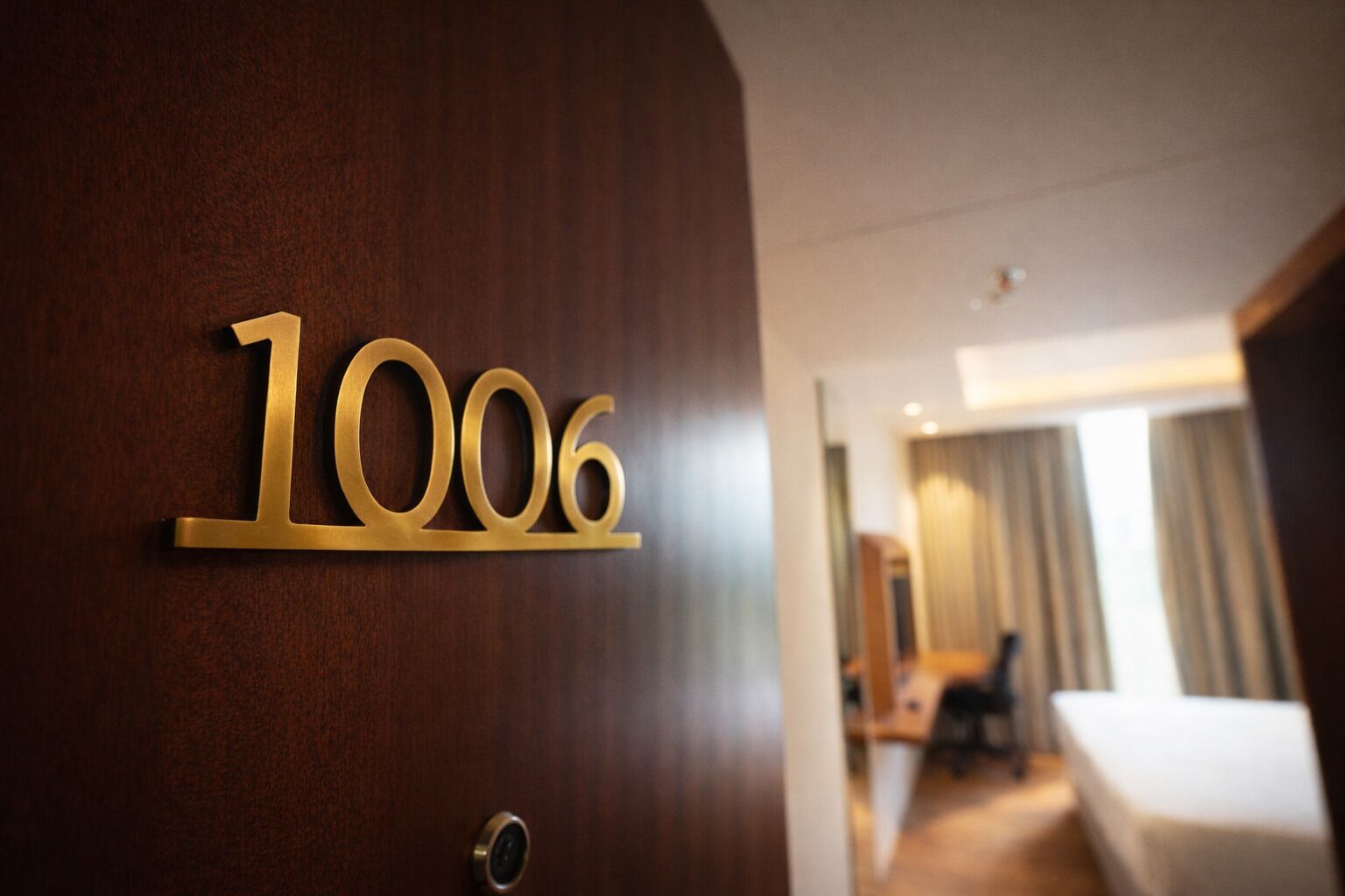 Habitación de hotel con puerta de madera que muestra el número 1006.