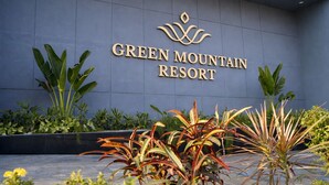 The exterior of Green Mountain Resort with a modern sign and tropical plants. - GREEN MOUNTAIN RESORT - Guna (Guna)