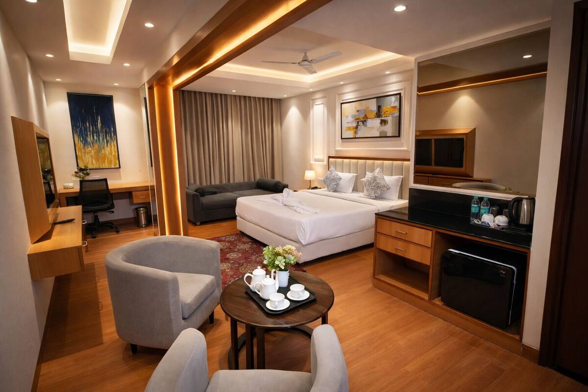 Habitación de hotel con cama, escritorio, silla, mesa de centro, televisor y minibar.