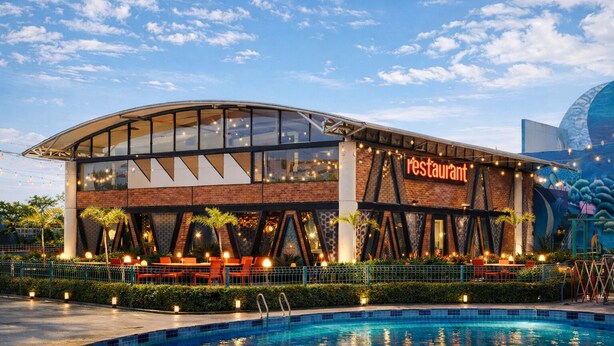 A modern restaurant with a curved glass facade, outdoor seating, and a pool area. - GREEN MOUNTAIN RESORT - Guna (Guna)