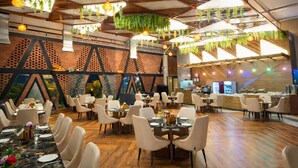 A spacious restaurant with high ceilings, hanging plants, and a variety of seating arrangements including round tables and chairs. - GREEN MOUNTAIN RESORT - Guna (Guna)