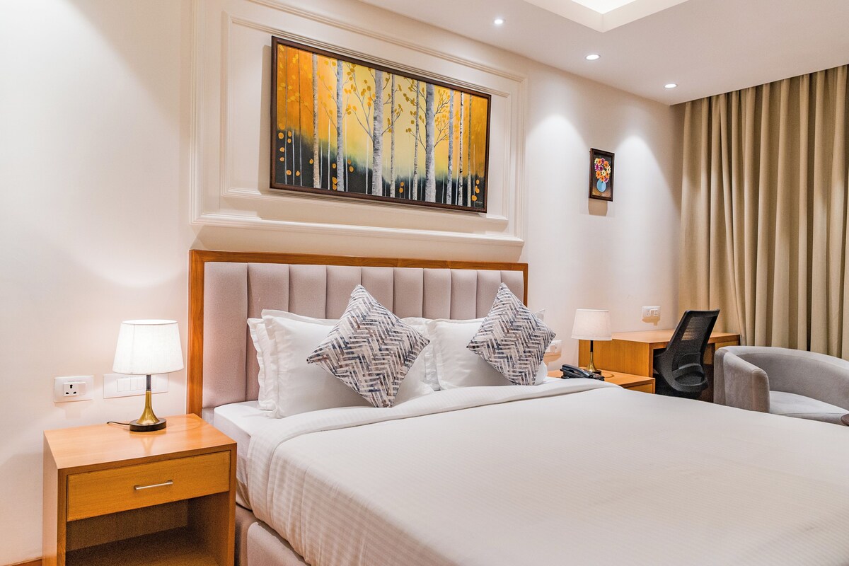 Una habitación de hotel con una cama grande, dos mesitas de noche, un escritorio y una silla.