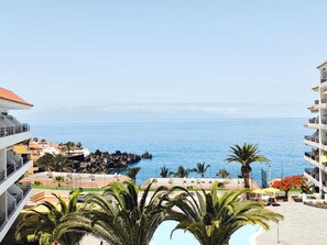 Un complexe hôtelier doté d’une piscine, de palmiers et offrant une vue sur l’océan.