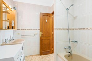 Une salle de bain avec une porte en bois, un lavabo, un miroir et une douche.