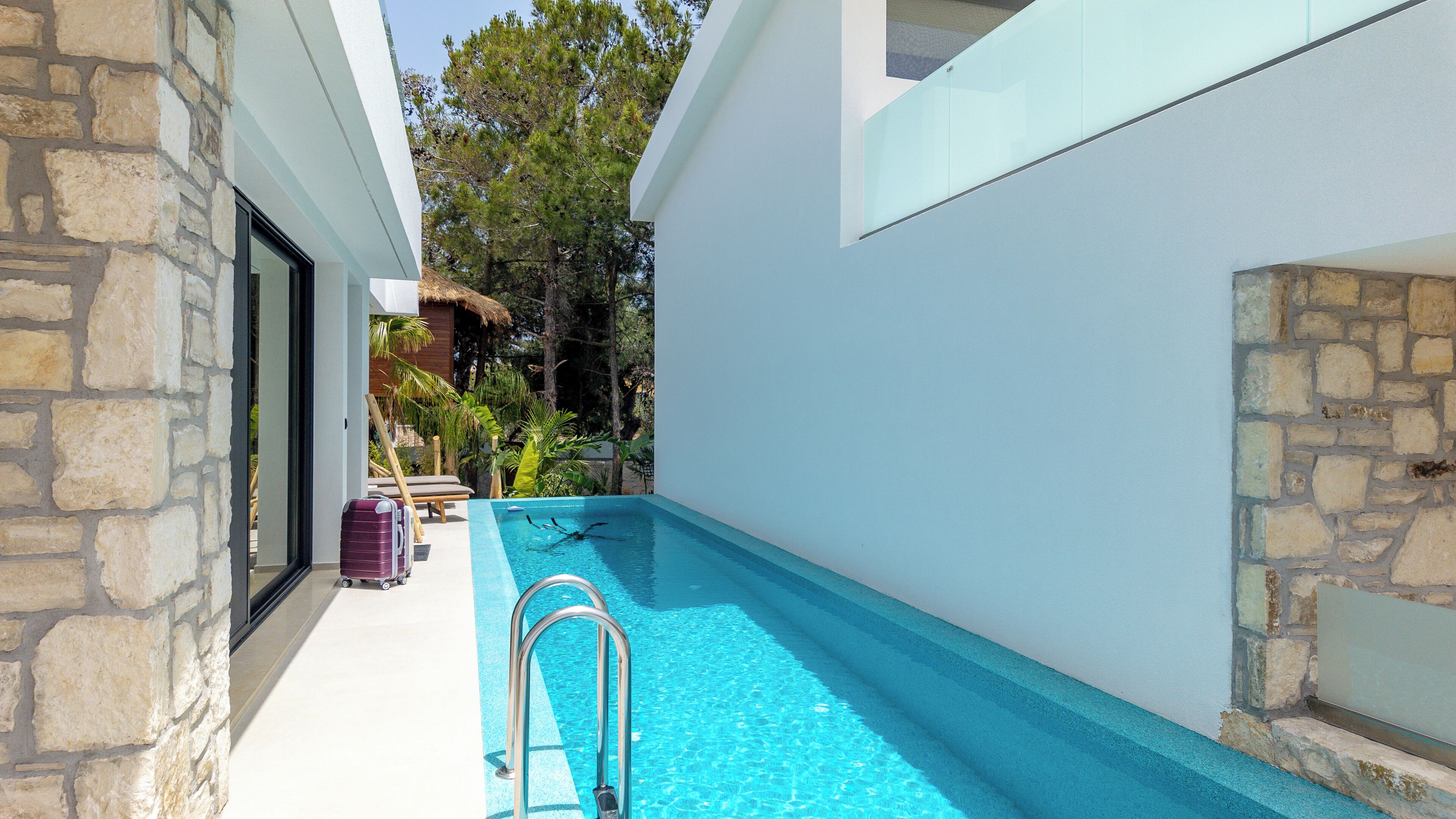 A swimming pool with a clear blue water, surrounded by stone walls and a wooden deck.