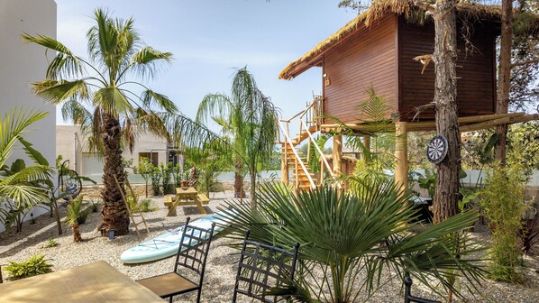 A patio with a wooden deck, a thatched-roof structure, and a dining area with a table and chairs. - D Palm Premium Living (Chania)
