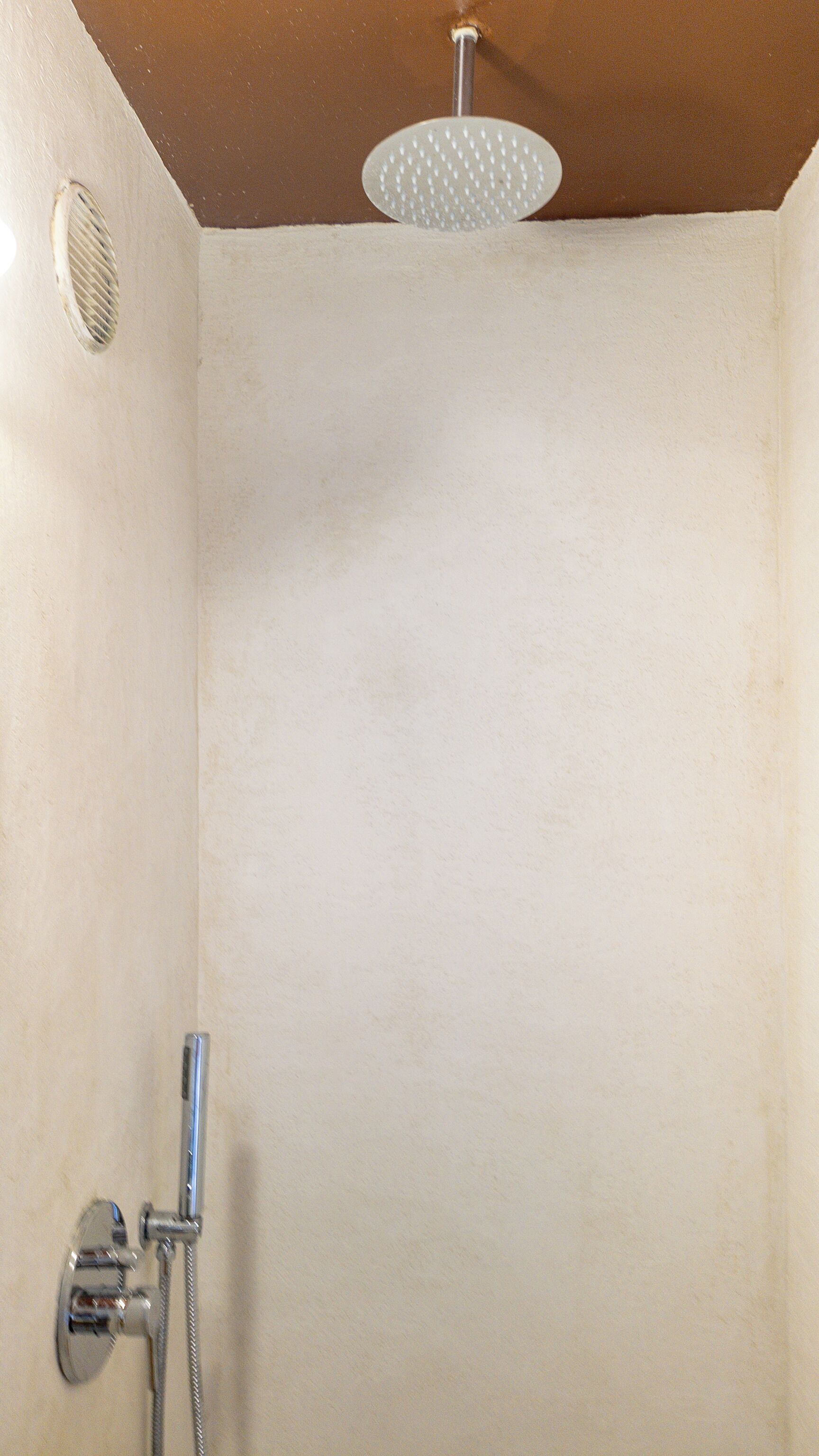 A shower with a handheld showerhead and a wall-mounted faucet.
